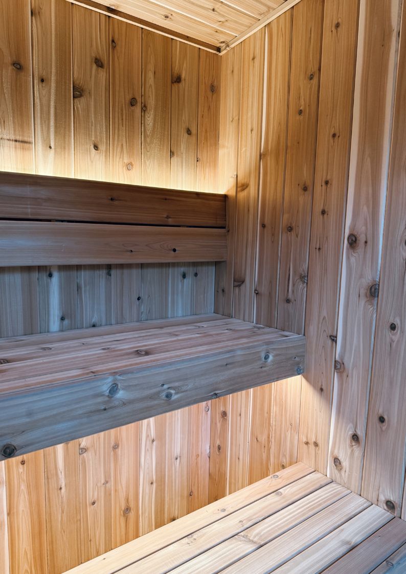 Sauna interior photograph showing cedar boards, benches and concealed lighting
